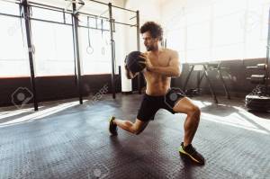 Muscular man exercising with medicine ball at gym